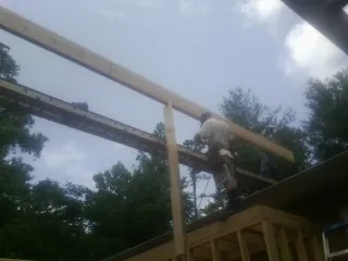 Carpenter setting a ridge beam over a new addition frame — Ice Dam Removal by Roofing Brothers in Lawrence