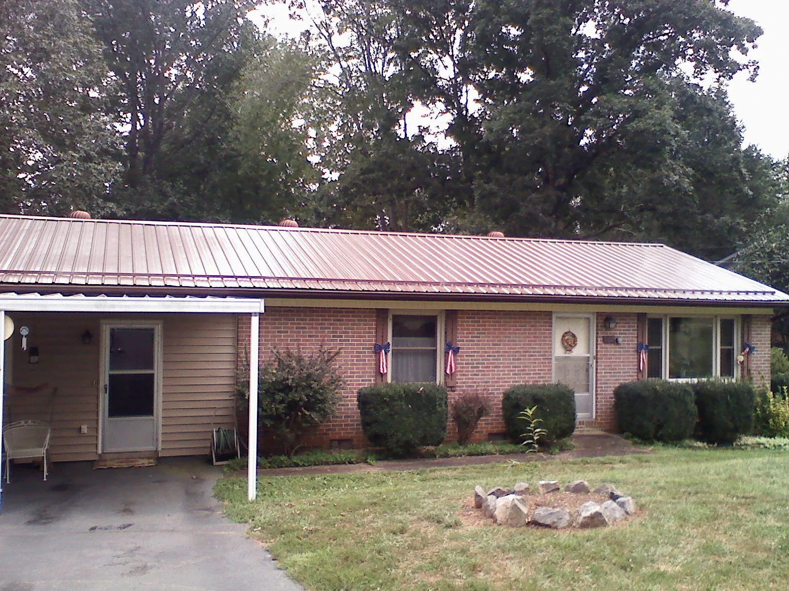 Bronze metal roof and carport on a brick ranch home — Roof Repair work by our crew in Lawrence